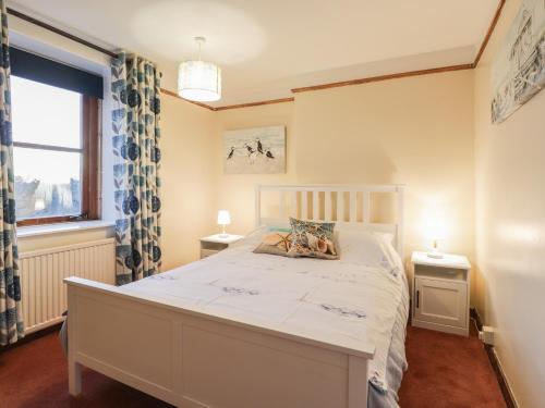 a bedroom with a large white bed and a window at Rowan Tree House in Brora