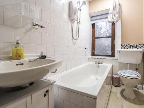 a bathroom with a sink and a tub and a toilet at Rowan Tree House in Brora
