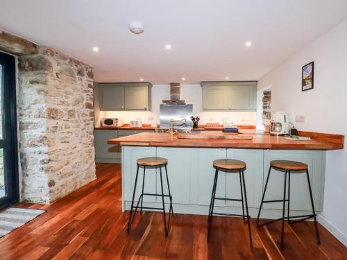 a kitchen with a counter and two bar stools at The Old Cattle Barn in Launceston
