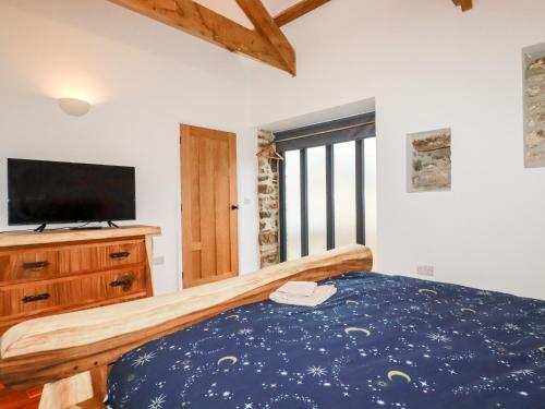 a bedroom with a bed and a tv on a dresser at The Old Cattle Barn in Launceston