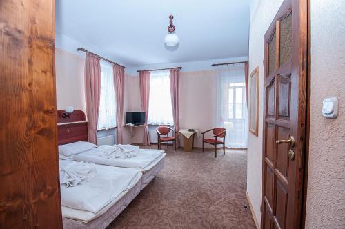 Cette chambre d'hôtel comprend deux lits, une table et des chaises. dans l'établissement Hotel Narcyz B, à Świeradów-Zdrój