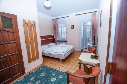 a small room with a bed and a table and chairs at Hotel Narcyz B in Świeradów-Zdrój