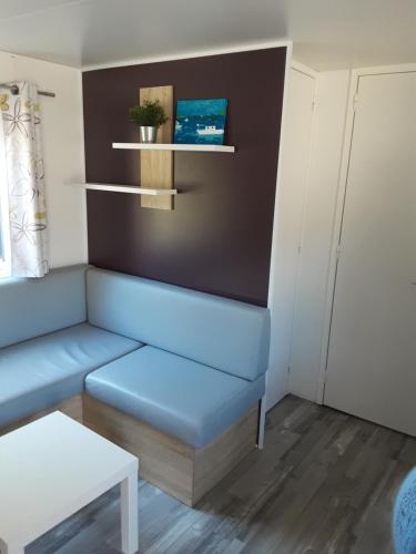 a living room with a blue couch and a table at Riva Bella chez Caraphou in Ouistreham