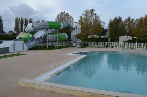 a pool with a water slide in a yard at Riva Bella chez Caraphou in Ouistreham