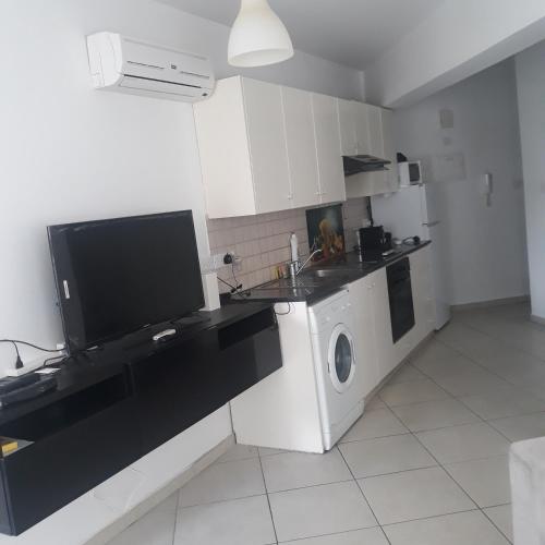 a white kitchen with a washer and dryer in it at A CHEERFUL APARTMENT in a popular area in Pallouriotissa