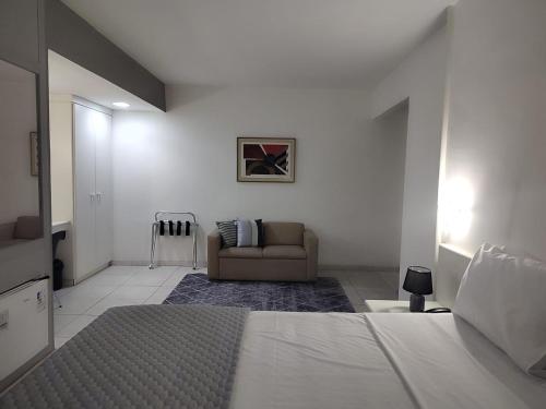 a white bedroom with a bed and a couch at Hotel Oscar Gold Savassi in Belo Horizonte