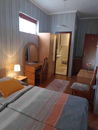 a bedroom with a bed and a desk and a bathroom at Valley Vendégház in Eger