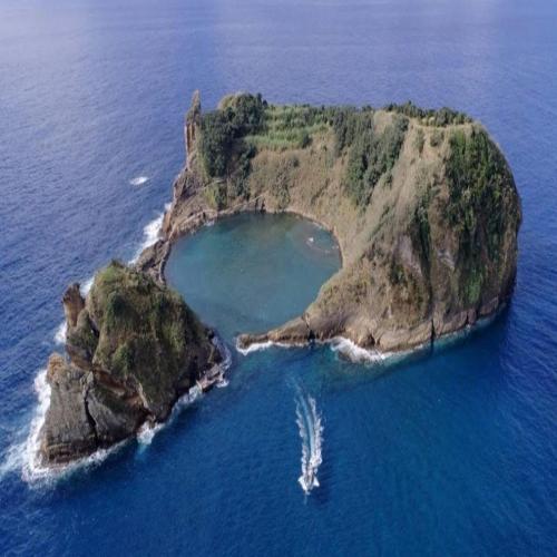 an island in the ocean with a boat in it at Alojamento CANTO NA RELVA in Ponta Delgada