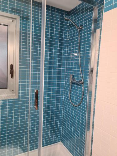 y baño con ducha de azulejos azules. en Quarto com banheiro privado em apartamento familiar, en Alicante