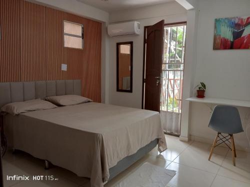 a bedroom with a bed and a chair and a window at Casa da Andrea Imbassai in Imbassai