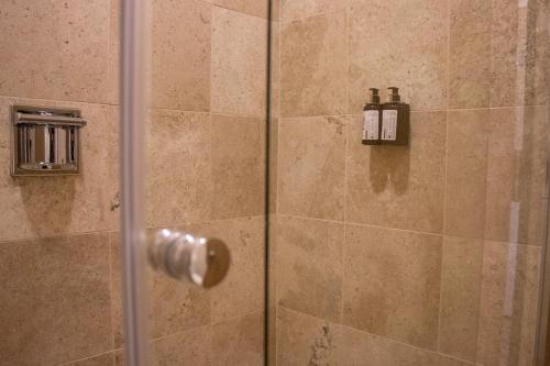 a shower with a glass door with two soap bottles at Hotel Turotel Morelia in Morelia