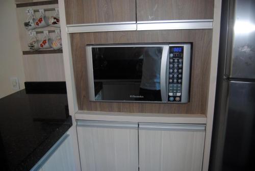 un microondas está integrado en los armarios de una cocina en Sobrado, en Itapema