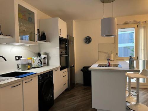 a kitchen with white cabinets and a black dishwasher at Cosy T2 au porte d’Orly-Rungis in Chevilly-Larue