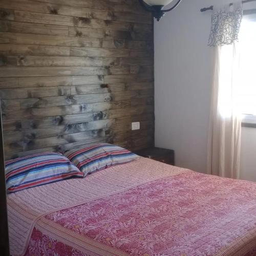 ein Schlafzimmer mit einer Holzwand und einem Bett mit Kissen in der Unterkunft Los Lapachos in Oro Verde