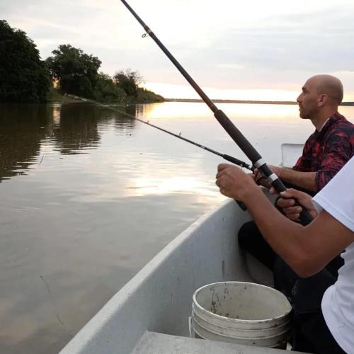 Un uomo seduto su una barca con una canna da pesca di Los Lapachos a Oro Verde