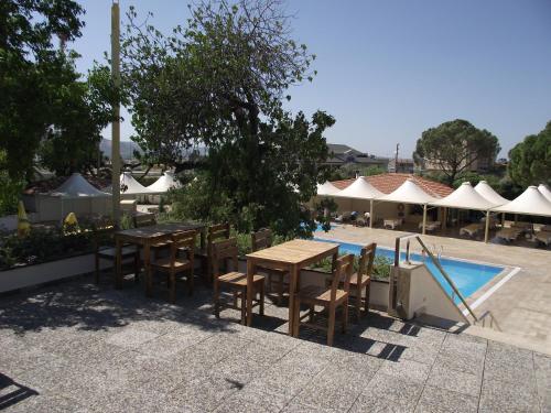 een patio met tafels en stoelen naast een zwembad bij Berksoy Hotel in Bergama