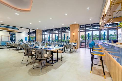 a dining room with tables and chairs and windows at TUI BLUE Nha Trang in Nha Trang