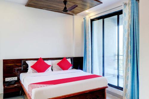 a bedroom with a bed with red pillows and a window at OYO Comfort lodging and boarding in Kalyan