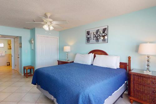 um quarto com uma cama azul e uma ventoinha de tecto em 107 - Sea Breeze em St. Pete Beach