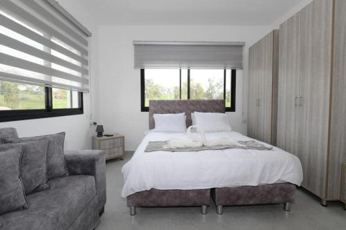 ein Schlafzimmer mit einem großen Bett und einem Sofa in der Unterkunft אחוזת העמק סוויטות בפוריה in Poriyya