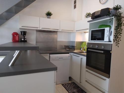 une cuisine avec des armoires blanches et un micro-ondes dans l'établissement Les Girelles - T2, 50m2 avec vue sur canal, à Palavas-les-Flots
