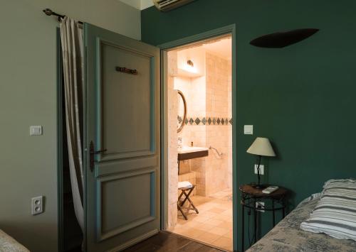 a bedroom with a door leading to a bathroom at Hôtel Mas Vidau Porte des Alpilles in Saint-Étienne-du-Grès