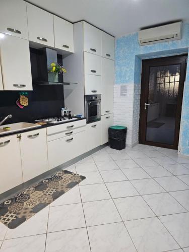 a large kitchen with white cabinets and a door at Appartamento sofí in Fiumicino