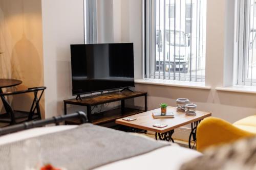 a living room with a flat screen tv and a table at Sea Breeze - Coast in Bournemouth