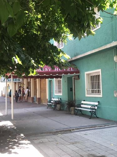a green building with two benches and an umbrella at Hotel Embassy in Miramar