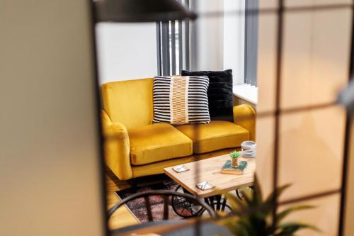 a yellow couch in a living room with a coffee table at Sea Breeze - Coast in Bournemouth