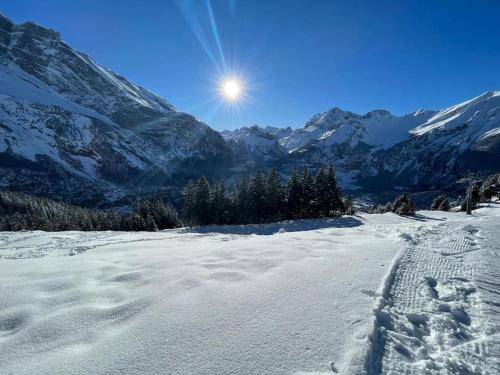 a snow covered mountain with the sun in the background at Chalet Spatz Garden near Oeschinen Lake in Kandersteg