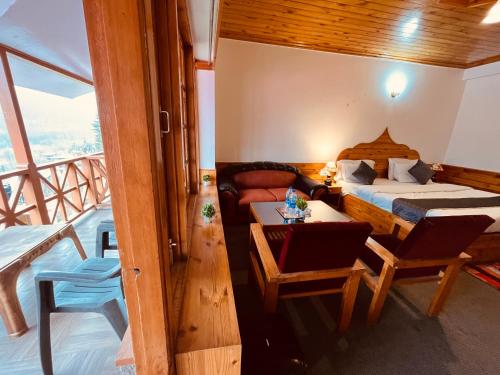 a bedroom with a bed and a couch and a table at Sita Hotel & Cottage, Manali in Manāli