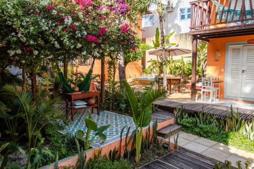 een tuin met een zwembad met bloemen en tafels bij Vila Charme in Jericoacoara