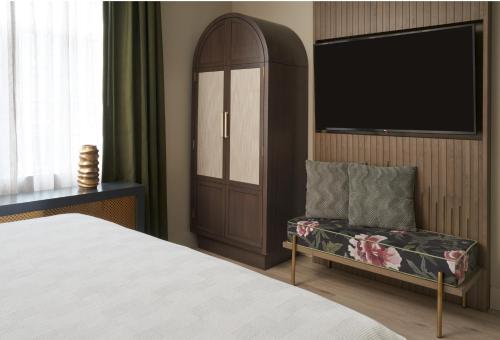 a bedroom with a bed and a tv and a chair at Hotel Vesper, Houston, a Tribute Portfolio Hotel in Houston
