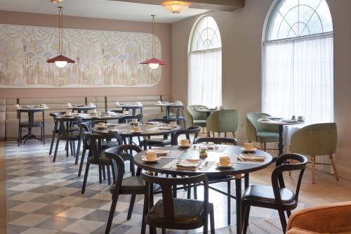 a dining room with tables and chairs and windows at Hotel Vesper, Houston, a Tribute Portfolio Hotel in Houston