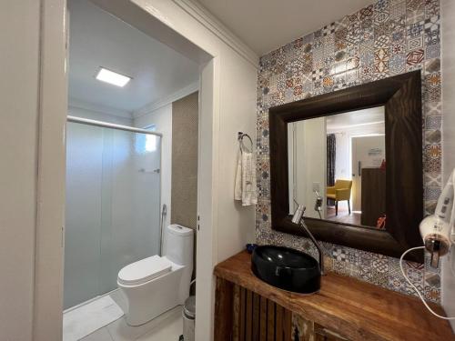 a bathroom with a toilet and a mirror at Apartamentos de Altitude Urubici in Urubici