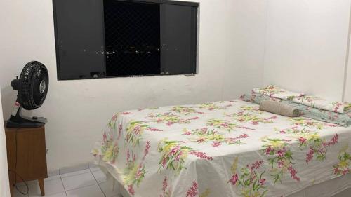 um quarto com uma cama com um cobertor florido e uma janela em Seu lugar no Carnaval do Recife! no Recife