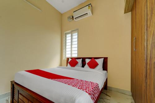 Un dormitorio con una cama con almohadas rojas y una ventana en Mm Home Stays en Irugūr