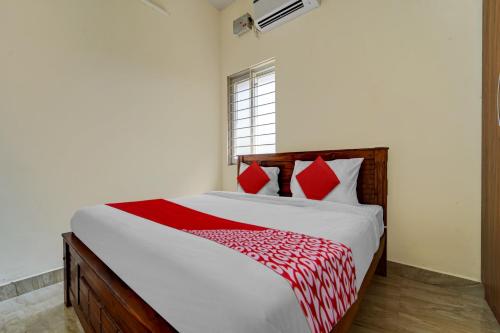 a bedroom with a large bed with red pillows at Hotel O MM Home Stays in Irugūr