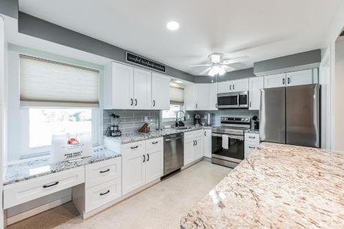 a kitchen with white cabinets and stainless steel appliances at Riverside Retreat: Deck Bar, FirePit, Boat Parking in Fort Myers