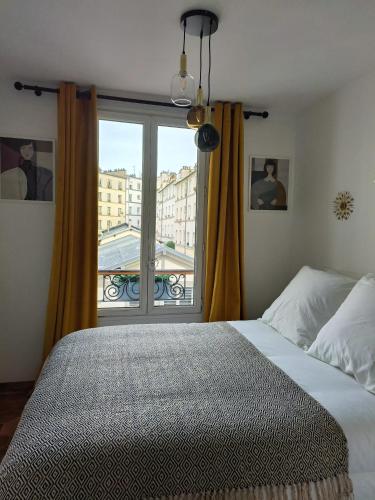 une chambre avec un lit et une grande fenêtre dans l'établissement 30m2 in the heart of Paris, à Paris