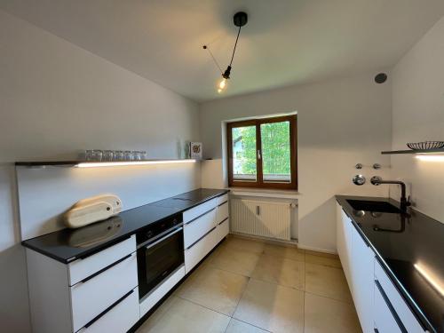 a kitchen with white cabinets and a black counter top at Moderne Ferienwohnung mit Zugspitzblick in Grainau