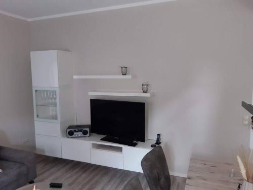 a living room with a flat screen tv on a white wall at FEWO Happe in Lennestadt