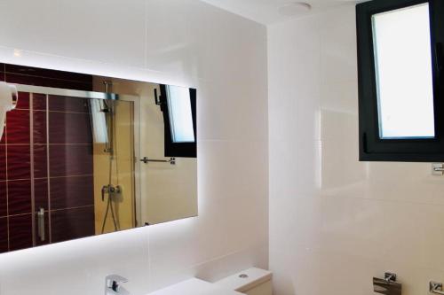 y baño con espejo, lavabo y ducha. en Villa SONIA, en Cala en Blanes