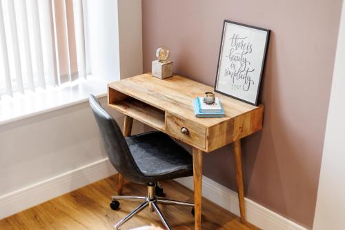 a wooden desk with a chair next to a window at Sea Breeze - Coast in Bournemouth