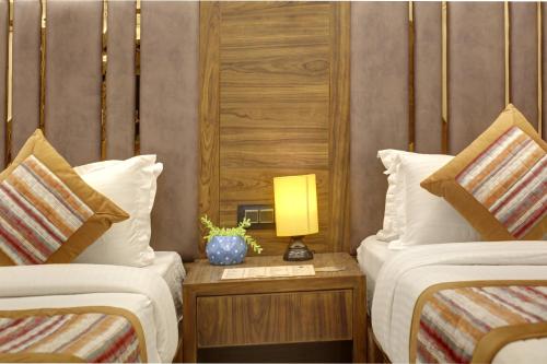 a hotel room with two beds and a lamp on a table at BLESS INN - Near Connaught Place in New Delhi