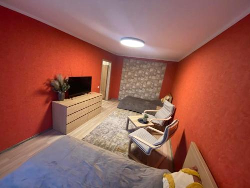 een slaapkamer met oranje muren en een bed en een tv bij Vieno kambario apartamentai 1 aukšte in Mažeikiai