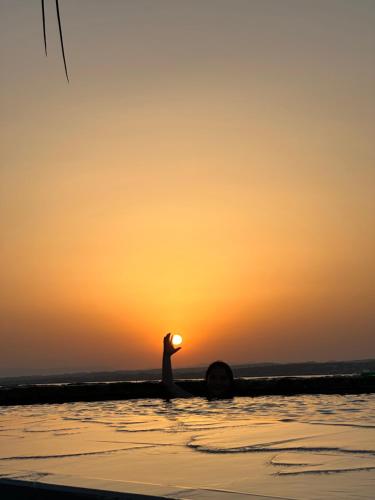 a person in the water with the sunset in the background at Les pieds dans l’eau in Sète