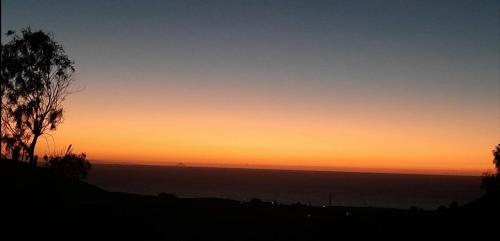 a sunset over the ocean with a tree in the foreground at Casagrande Sunset II - Fuerteventura - Costa Calma in Pájara