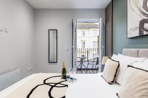 a white bedroom with a bottle of wine on a bed at Sea Breeze - Coast in Bournemouth